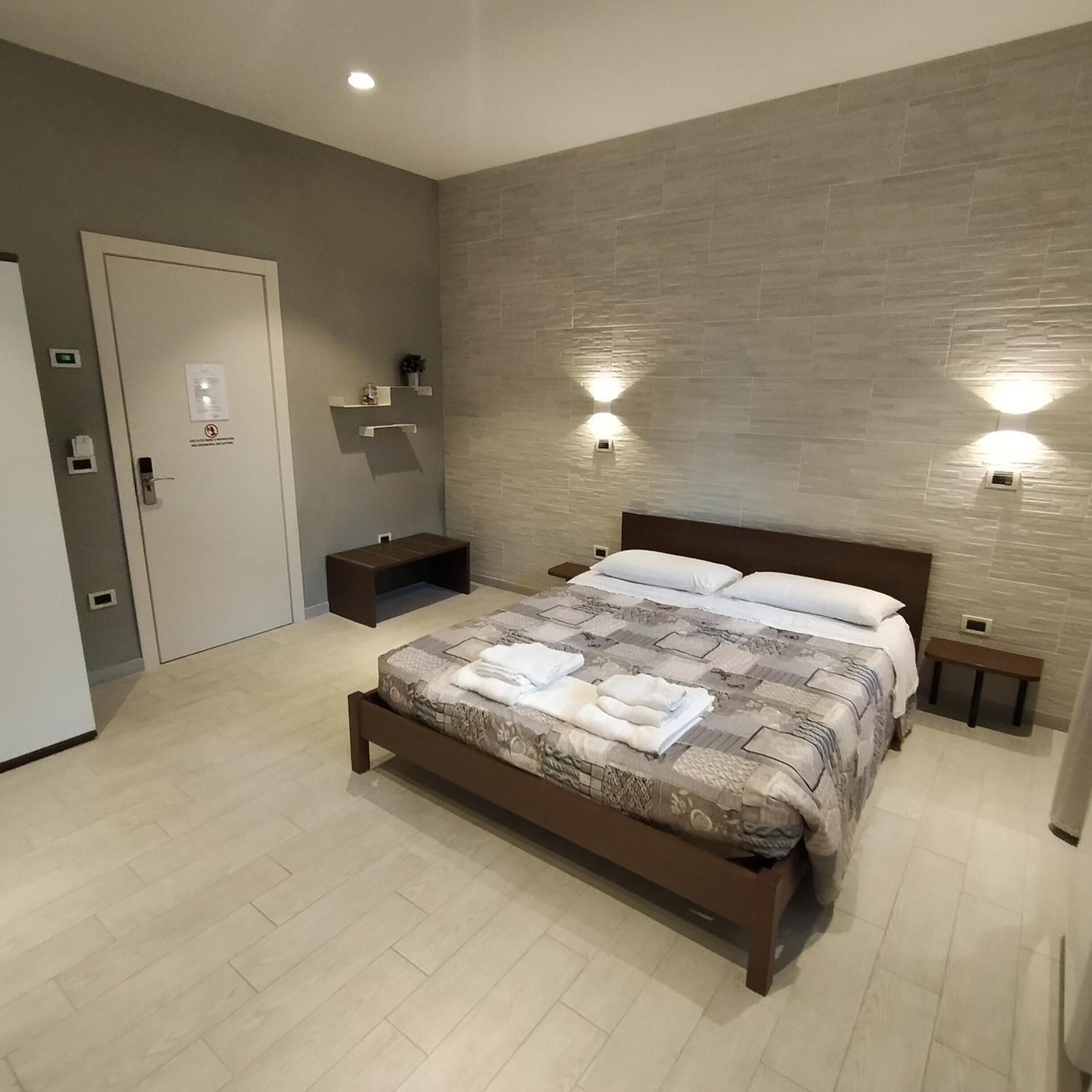 A modern bedroom with a wooden bed, bedside tables, and built-in wall lighting.