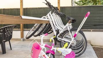 A bicycle rack with a white bicycle and a pink children's bicycle.