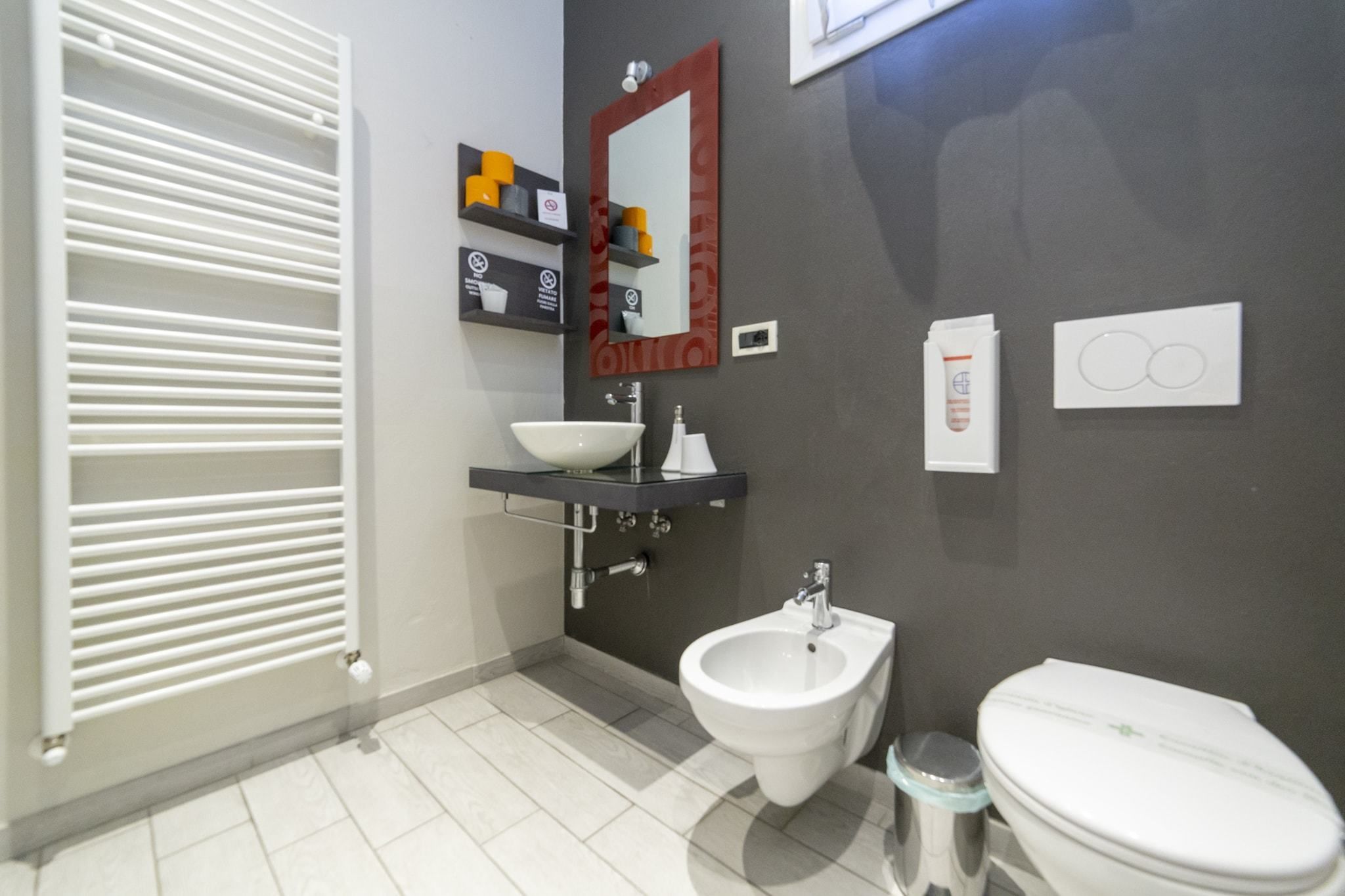 A modern bathroom with a bidet, toilet, and a large mirror.