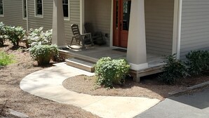 A two-story house with a covered porch, a front door, and a driveway leading to the entrance.