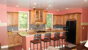 A modern kitchen with wooden cabinets, a black refrigerator, and a bar area with stools.