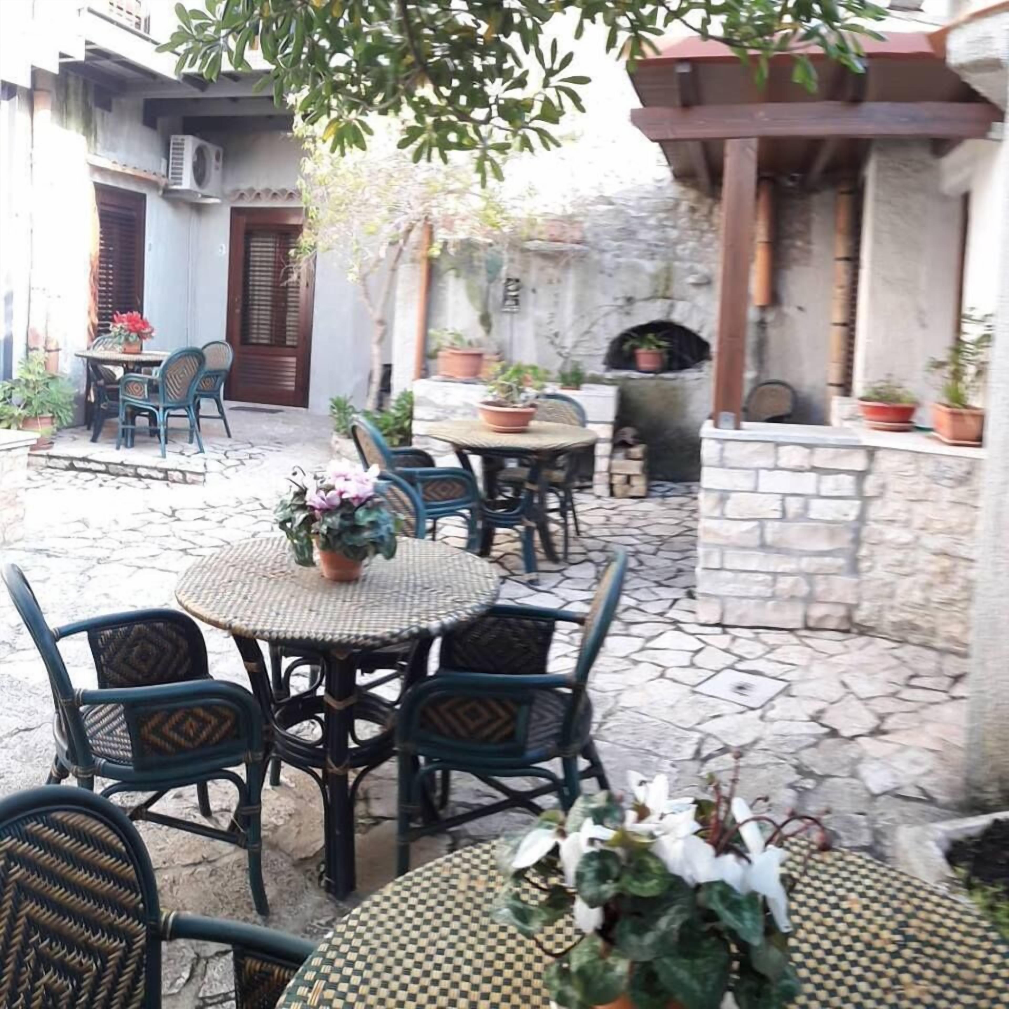 An outdoor patio area with stone flooring, wicker furniture, and potted plants.