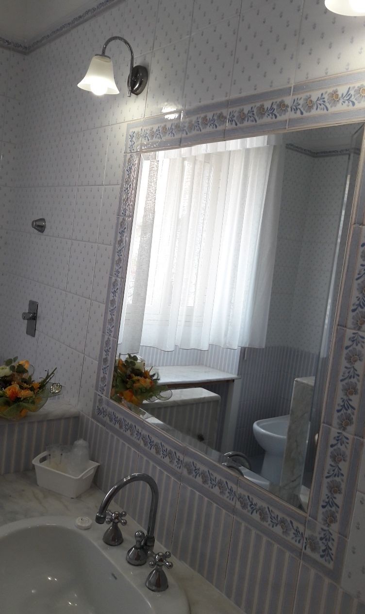 A bathroom with a large mirror, two sinks, a shower, and a toilet.