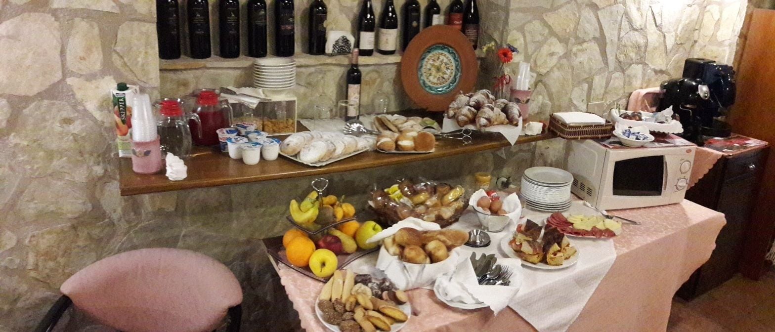 A breakfast buffet with various food items, a coffee machine, and wine bottles on shelves.