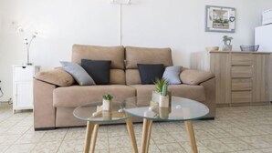 Un salon avec un canapé beige, deux tables en verre et un meuble.