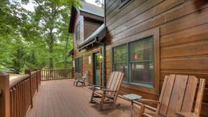 A wooden deck with outdoor seating and a building with large windows. - GOT IT ALL U ALL  Pool Table , Arcade ,Hot Tub , Pools,Free WIFI,Pet Friendly ! (Sevierville)