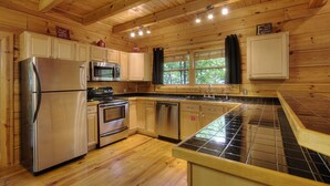 A wooden cabin kitchen with a stainless steel refrigerator, microwave, oven, and dishwasher. - GOT IT ALL U ALL  Pool Table , Arcade ,Hot Tub , Pools,Free WIFI,Pet Friendly ! (Sevierville)