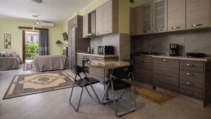 A modern kitchen with wooden cabinets, a round dining table, and two black chairs. - Pappas Family House (Ναύπλιο)