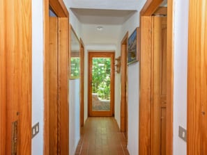 Stunning views of lush greenery await in this serene room, accessible through a hallway with a tiled floor and recessed lighting.