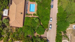 An aerial view of a house with a tiled roof, a swimming pool, and a driveway with cars parked. - Maximilian by Interhome (Portobello)