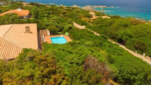 A coastal property with a swimming pool surrounded by lush greenery, a clear view of the sea, and terraced buildings. - Maximilian by Interhome (Portobello)
