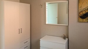 Um quarto com um guarda-roupa branco, uma cômoda branca e um espelho sobre a cômoda.