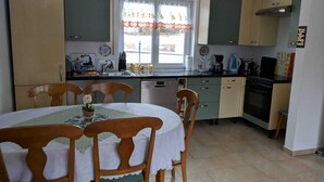 Cozinha compacta com área de refeições, com mesa e cadeiras, pia, fogão e armários.