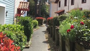 A narrow pathway flanked by wooden fences and houses with red and white exteriors. - House 6/8 pers in holiday resort - pine forest, ocean, lake, your choice! (Lacanau Océan)
