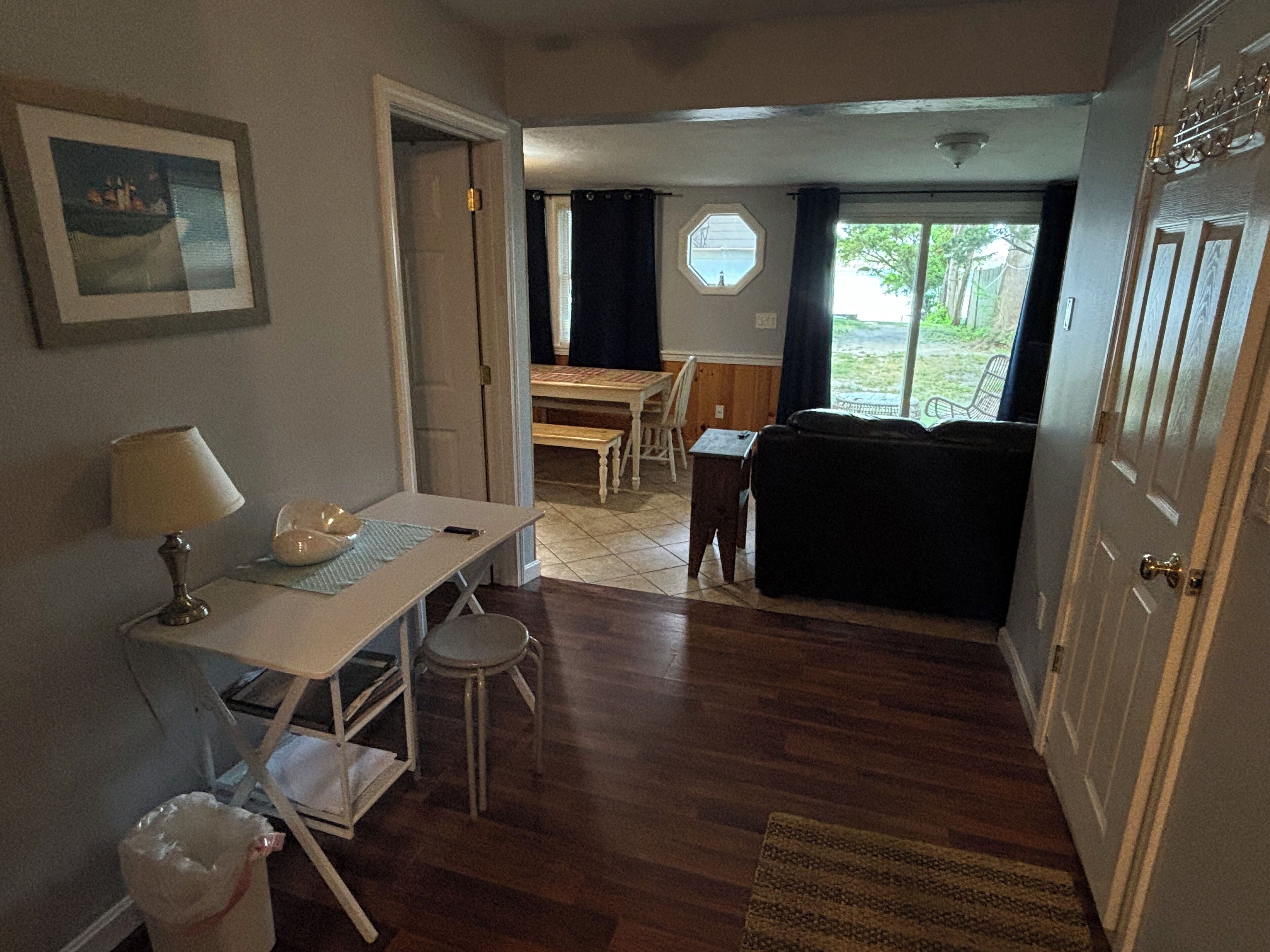 Un espace de vie compact comprenant un coin repas, un canapé, une petite table avec une lampe et une poubelle.