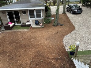 A residential property with a covered patio, a small outdoor seating area, and a gravel driveway.