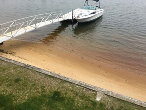 A boat docked at a concrete pier with a sandy shore in the background.