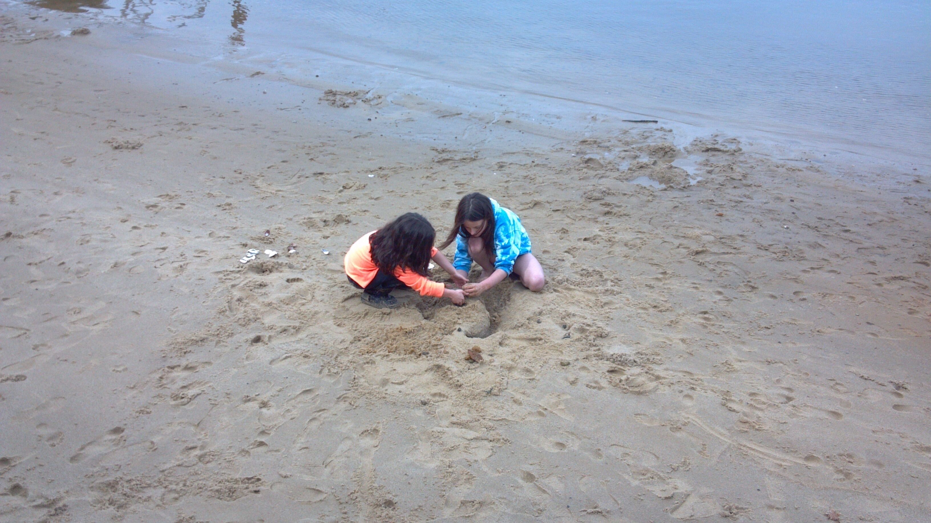 Dos niños jugando en la arena de una playa.