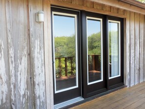 Facciata in legno con porte in vetro a cornice nera che si aprono su un balcone.