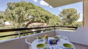 Ein Balkon mit einem Tisch für zwei Personen, einer Orangensaftflasche und einer Tüte Snacks.
