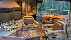 A rustic wooden deck with a ping pong table, two wooden chairs, a table with a checkered game, and a wood-burning stove. - Damiro (Piriapolis)