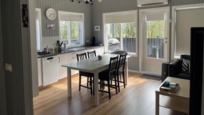 Une cuisine moderne avec un coin repas, dotée d’une grande fenêtre, d’appareils électroménagers intégrés et d’un ventilateur de plafond.