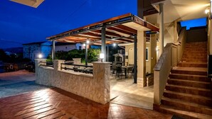 An outdoor patio area with a covered seating area, a stone wall, and a staircase leading to an upper level. - Studio apartment in Lopar with Terrace, Air condition, WIFI (4739-1) (Lopar)