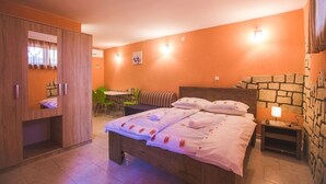 A bedroom with a bed, a wooden wardrobe, a small table with a chair, and a stone wall. - Studio apartment in Lopar with Terrace, Air condition, WIFI (4739-1) (Lopar)