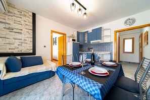 Zona pranzo con tovaglia a scacchi, divano e cucina sullo sfondo.
