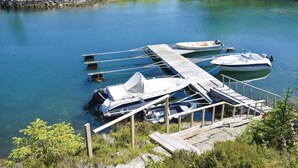 A dock with boats, a wooden pier, and a rocky shoreline.