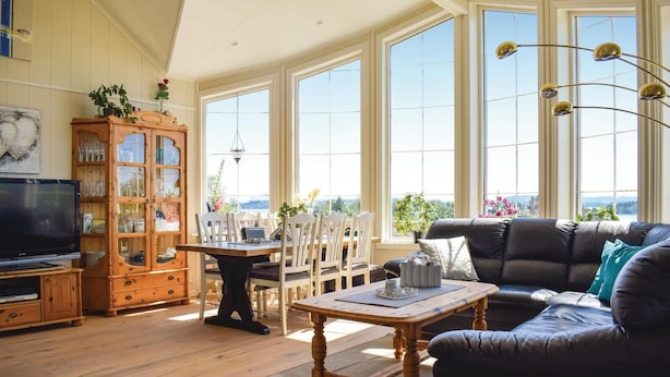 A spacious living room with a large window, a wooden cabinet, a sofa, and a dining table.