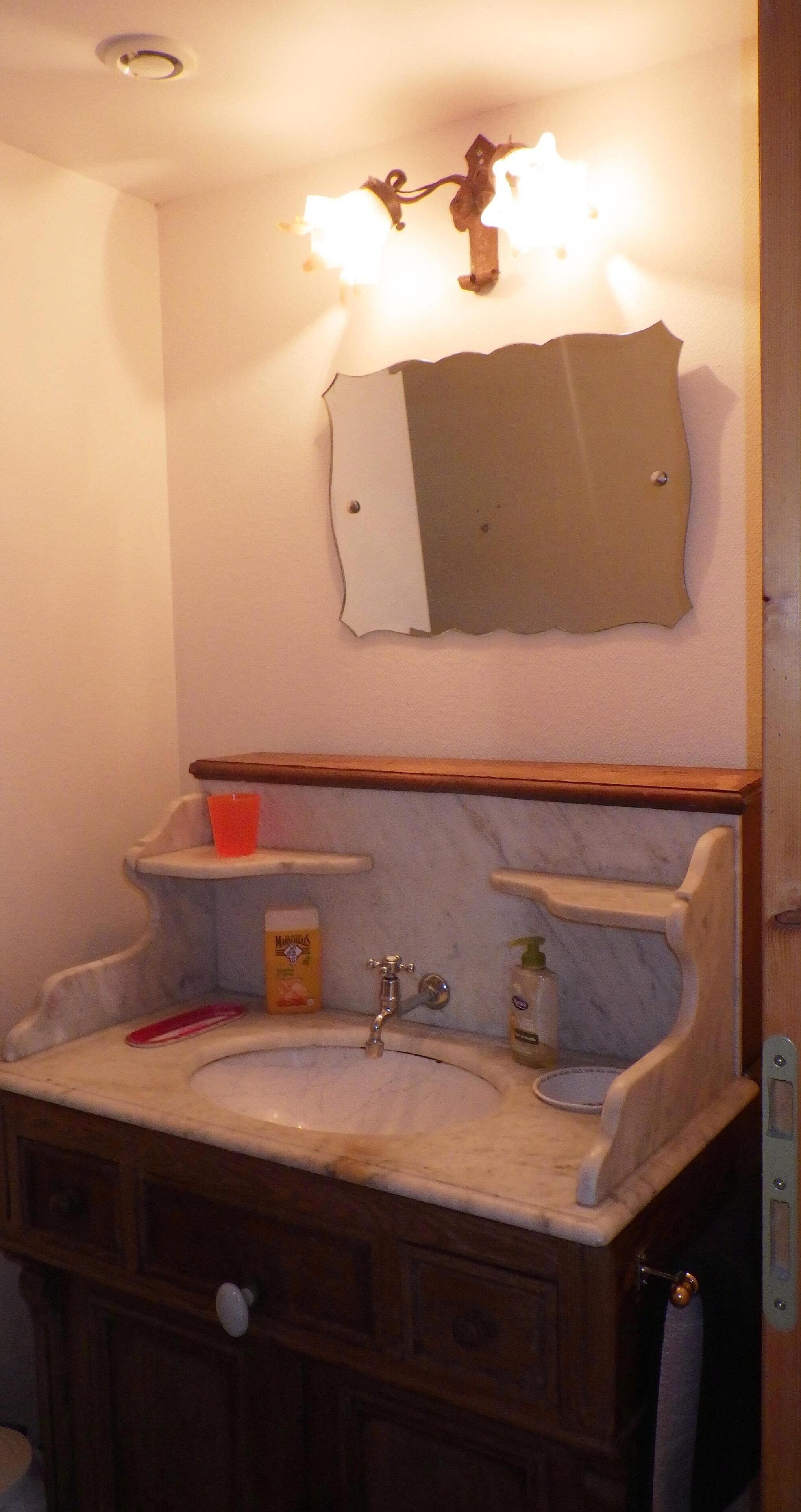 Ein Badezimmer mit Waschbecken, Spiegel und Ablageflächen.