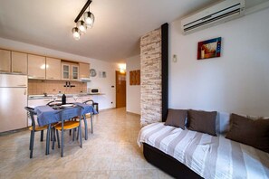 Un espacio habitable compacto con kitchenette, comedor y cama con manta a rayas.