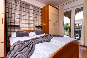 Un dormitorio con cama, armario y balcón con mobiliario exterior.
