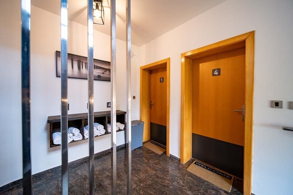 Un couloir avec deux portes en bois, numérotées 4 et 5, et une étagère où sont pliées des serviettes.