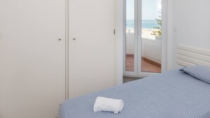 A bedroom with a bed, a white wardrobe, and a sliding glass door leading to a balcony with a beach view. - Beny's Beach House - 2 min walk to the rock beach (Portimão)