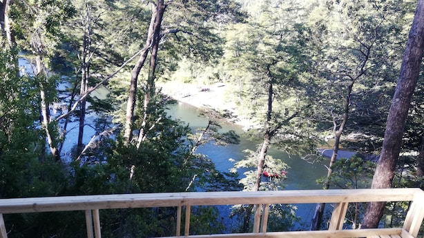 Una terraza de madera con vistas a un área boscosa y un río.