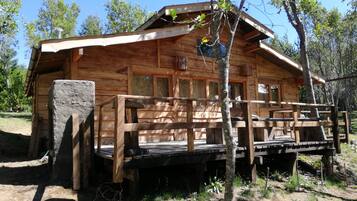 A wooden cabin with a porch and a stone base.