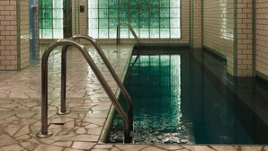 An indoor swimming pool with tiled walls and a clear glass barrier. - Hotel Le Ballu (Paris)