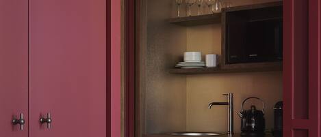 A compact kitchen with wooden cabinets, a stainless steel sink, and a microwave above the counter.