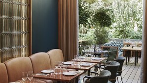 A restaurant with a long dining table, cushioned seating, and hanging pendant lights. - Hotel Le Ballu (Paris)