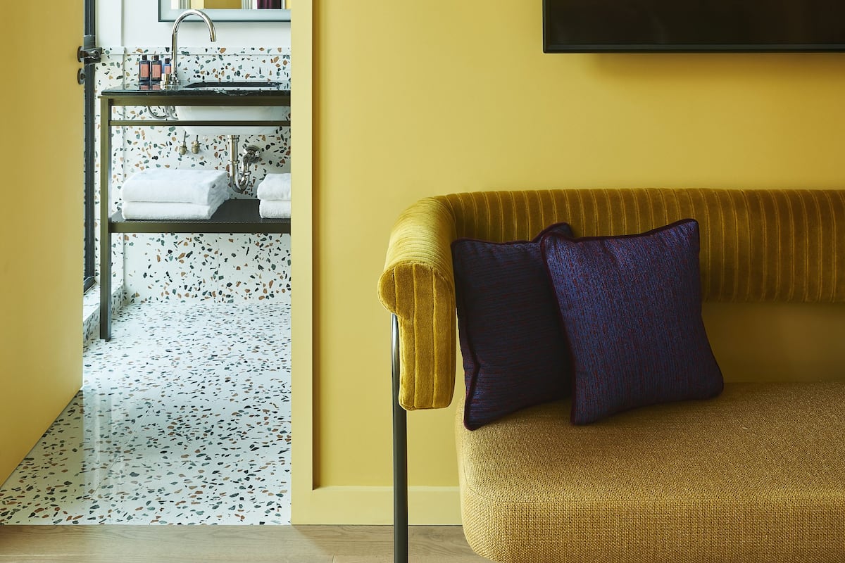 A modern living room with a sofa, a flat-screen TV, and a kitchen area in the background.