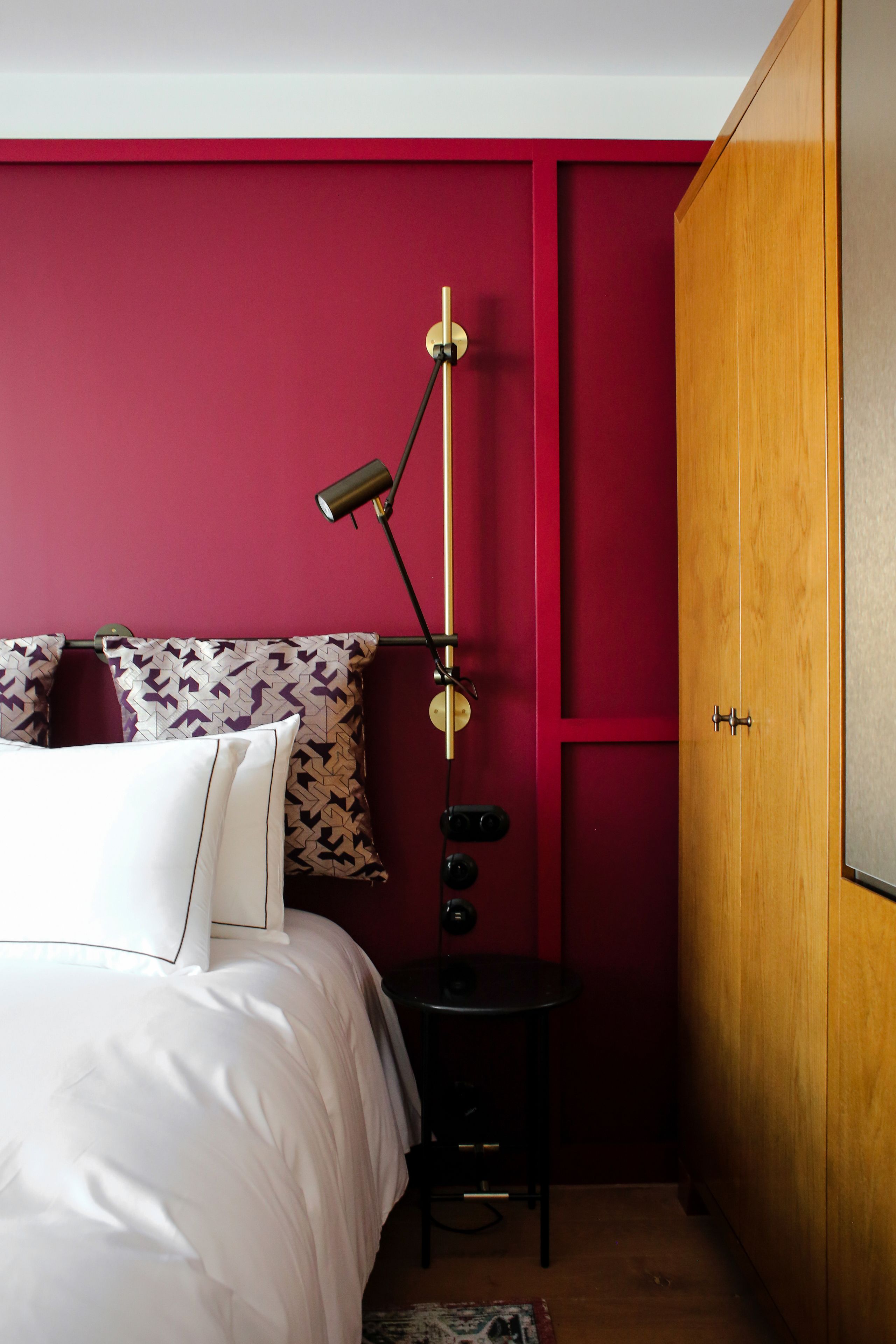 A bedroom with a bed, a nightstand, a lamp, and a wardrobe.