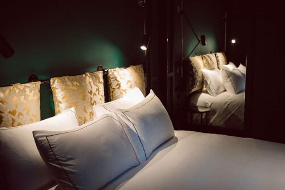 A hotel room with a bed, a chair, and a mirror.