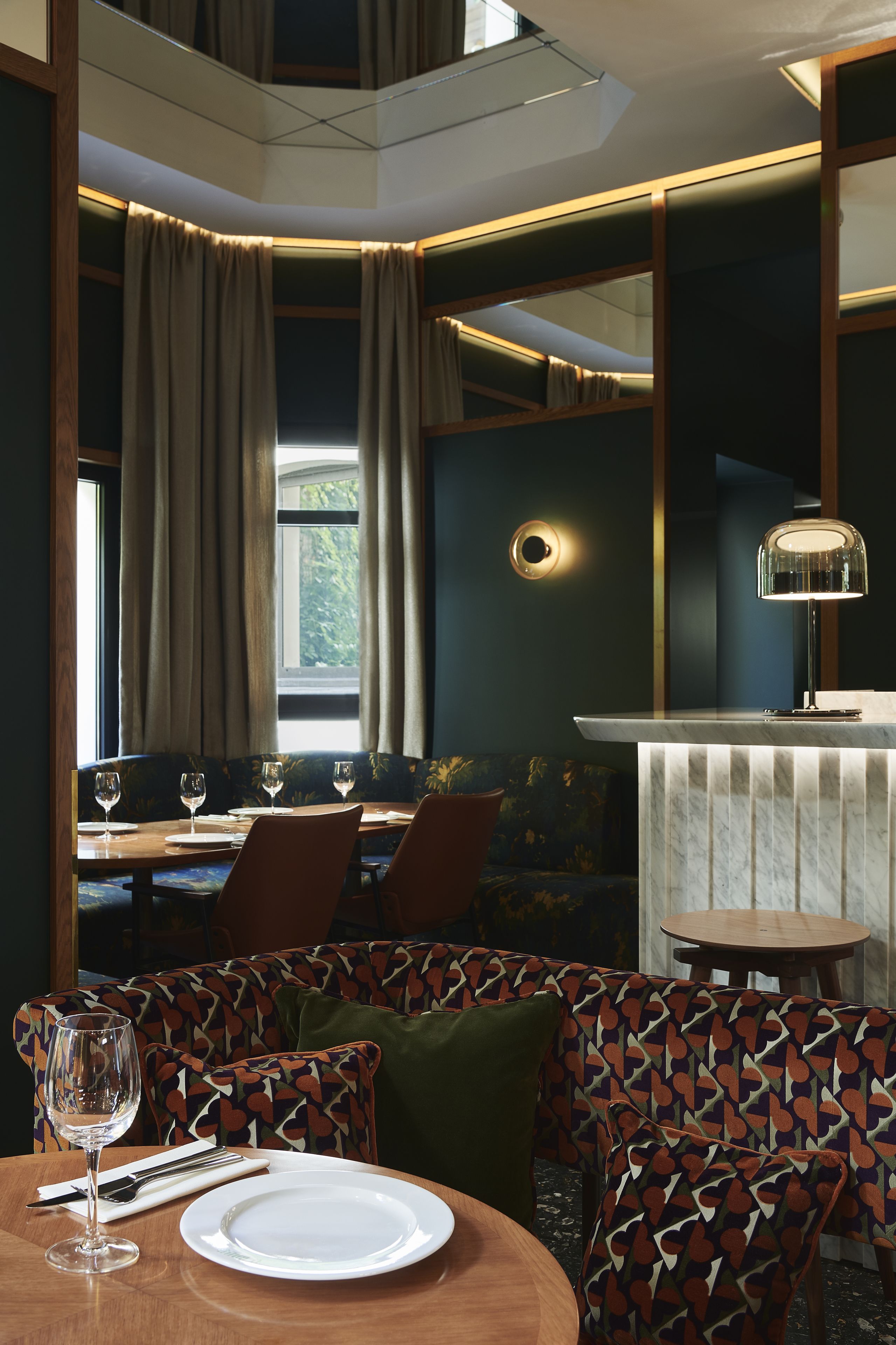 A dining area with a round table, chairs, and a bench with patterned cushions.