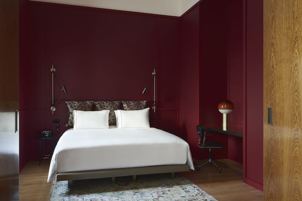 A bedroom with a large bed, a desk, and a chair.