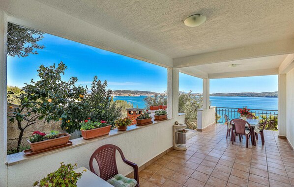 A covered outdoor area with a view of the sea, potted plants, and a table with chairs. - Gorgeous apartment in Seget Donji with WiFi (Seget Donji)
