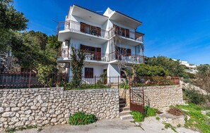 A multi-story building with balconies, a stone wall, and a clear sky. - Gorgeous apartment in Seget Donji with WiFi (Seget Donji)
