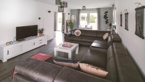 A modern living room with a sectional sofa, a flat-screen TV, a coffee table, and a dining area with a table and chairs. - Pet friendly home in Zeewolde with WiFi (Zeewolde)