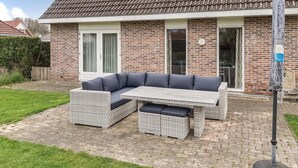 A patio with a wicker sofa and table, a brick house, and a metal pole. - Pet friendly home in Zeewolde with WiFi (Zeewolde)